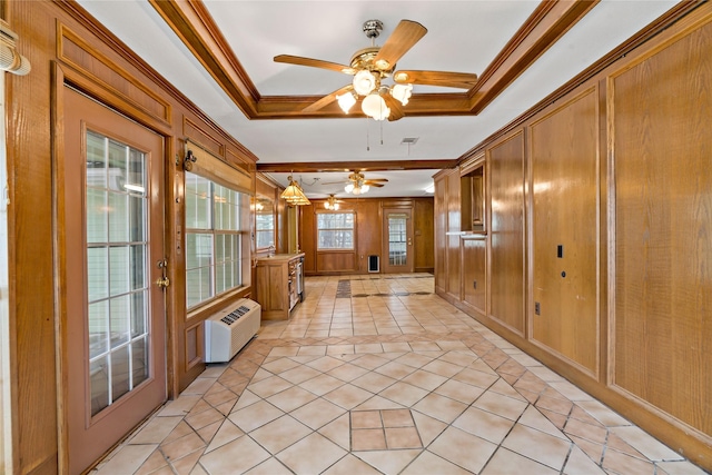 interior space featuring a tray ceiling, a wall unit AC, light tile patterned floors, ornamental molding, and wood walls