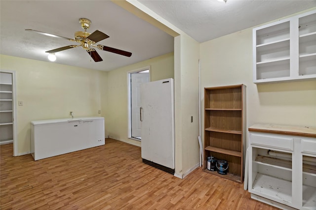 unfurnished living room featuring light wood-type flooring, ceiling fan, and a textured ceiling