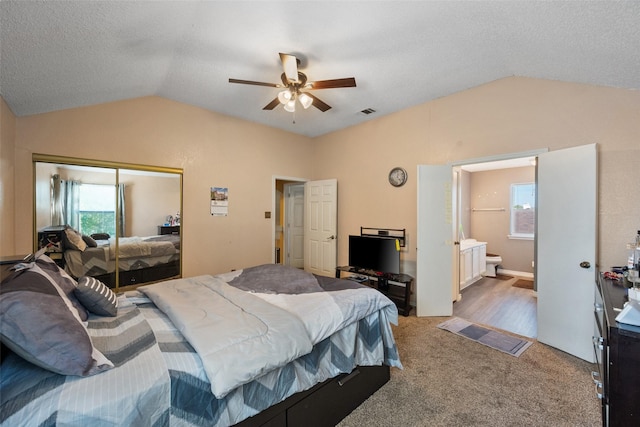 carpeted bedroom with a textured ceiling, multiple windows, vaulted ceiling, and a closet