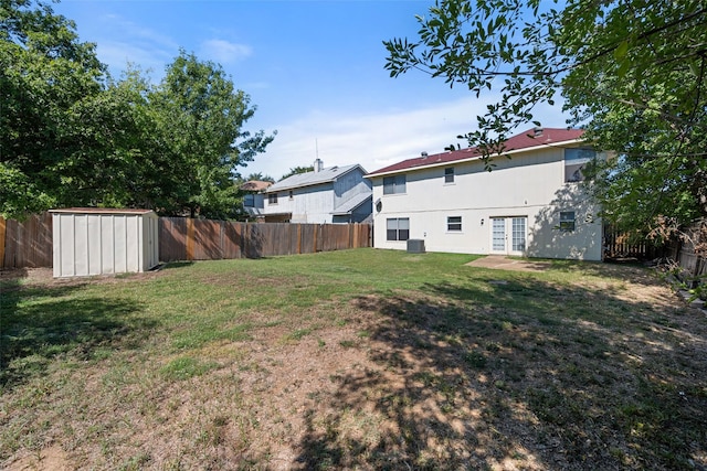 view of yard featuring french doors, a fenced backyard, and a storage shed