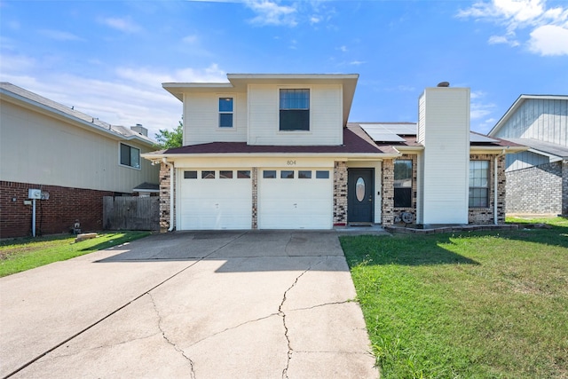 traditional home featuring concrete driveway, an attached garage, fence, roof mounted solar panels, and a front lawn