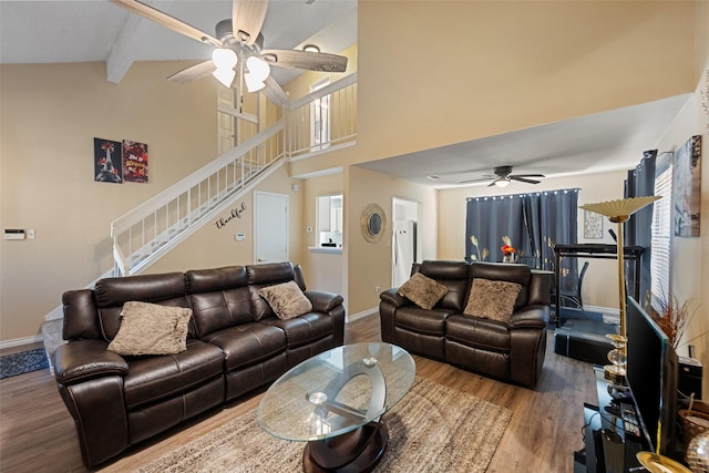 living room with baseboards, a ceiling fan, wood finished floors, stairs, and beam ceiling