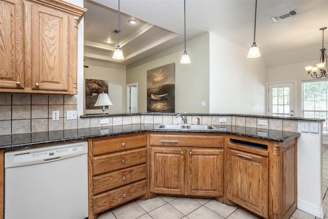 kitchen featuring tasteful backsplash, a raised ceiling, visible vents, white dishwasher, and a sink