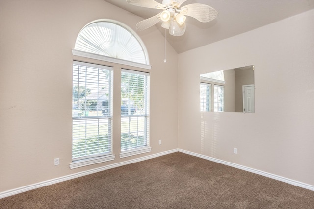 unfurnished room featuring lofted ceiling, ceiling fan, dark carpet, and a wealth of natural light