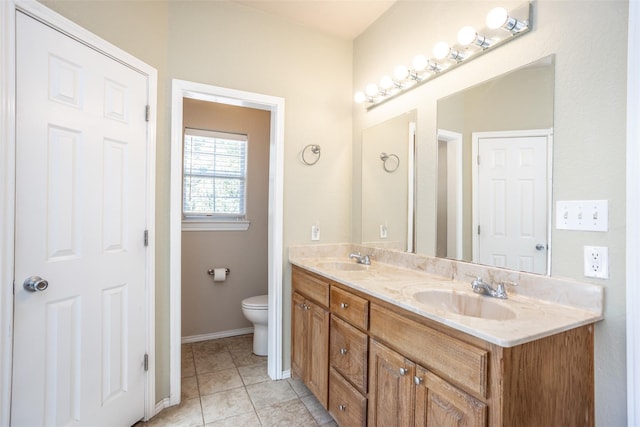 full bathroom with toilet, double vanity, a sink, and tile patterned floors