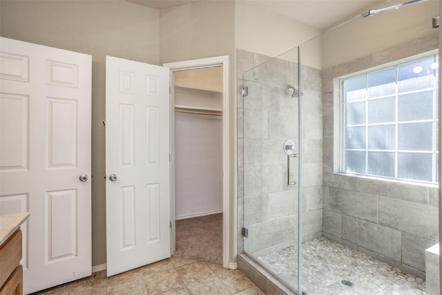 bathroom featuring a stall shower, vanity, a walk in closet, and tile patterned floors