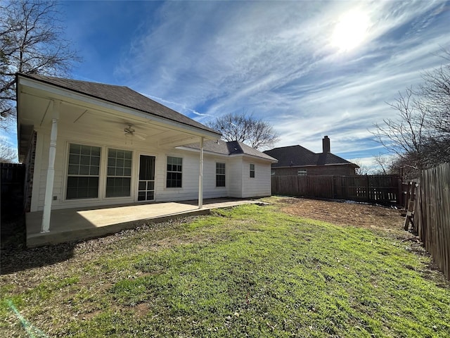 rear view of property featuring a patio, a fenced backyard, a shingled roof, a ceiling fan, and a lawn