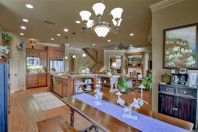 dining area featuring stairway, light wood-type flooring, visible vents, and crown molding