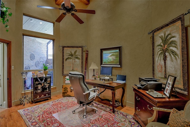 office with ceiling fan, a high ceiling, wood finished floors, and a textured wall