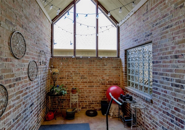 exercise area with brick wall, plenty of natural light, and rail lighting