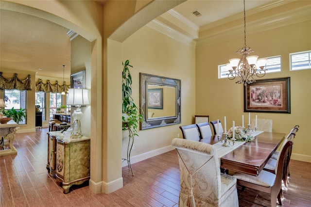 dining area featuring arched walkways, crown molding, wood finished floors, baseboards, and an inviting chandelier