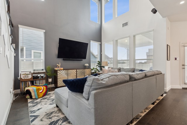 living area featuring baseboards, wood finished floors, visible vents, and a healthy amount of sunlight