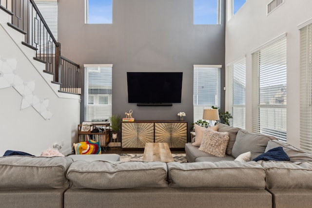 living area with stairway, visible vents, and a healthy amount of sunlight