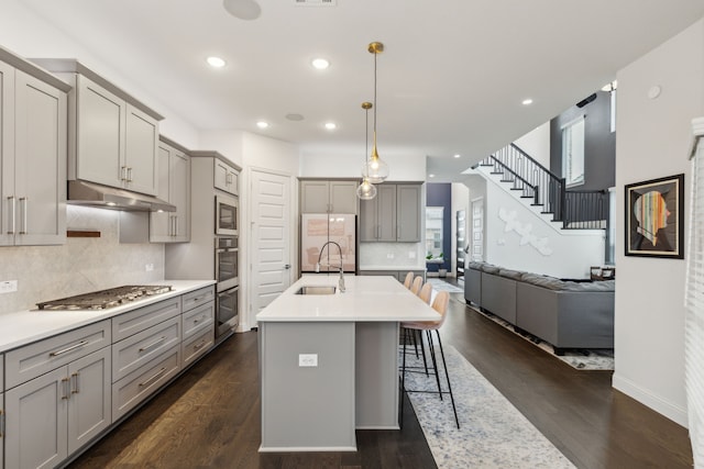 kitchen featuring freestanding refrigerator, a sink, under cabinet range hood, and gray cabinetry