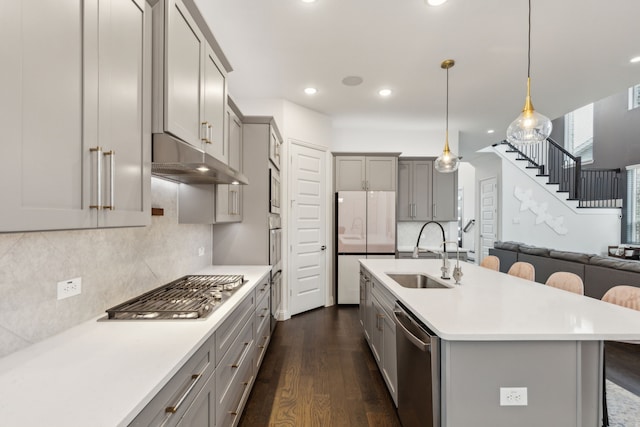 kitchen with stainless steel appliances, dark wood-style flooring, a sink, light countertops, and gray cabinets