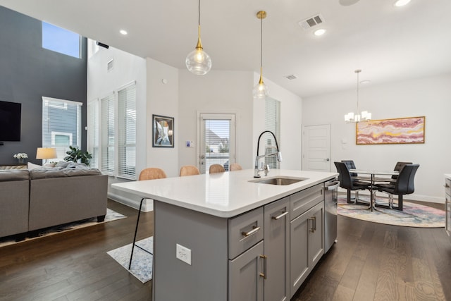 kitchen featuring visible vents, dark wood finished floors, a kitchen breakfast bar, gray cabinetry, and a sink