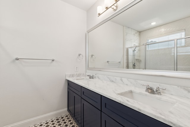 bathroom featuring a sink, a tile shower, baseboards, and double vanity