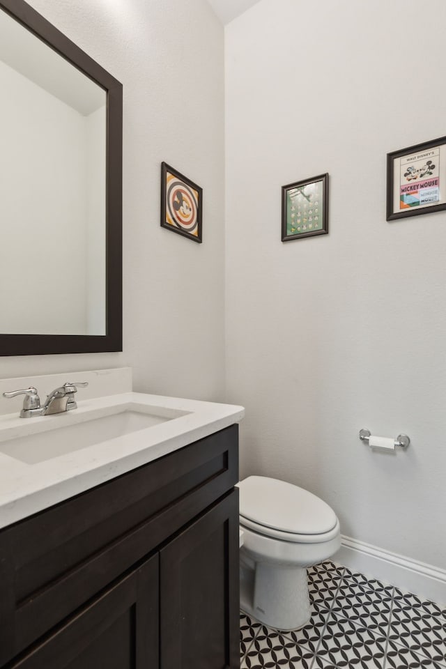 bathroom featuring toilet, vanity, and baseboards