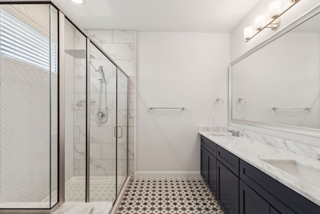 full bath featuring a sink, a shower stall, baseboards, and double vanity