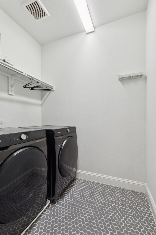 clothes washing area featuring laundry area, baseboards, visible vents, and washer and clothes dryer