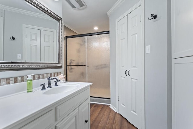 bathroom featuring visible vents, ornamental molding, wood finished floors, vanity, and a shower stall