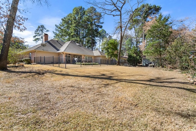 back of house featuring a chimney, fence, and a lawn