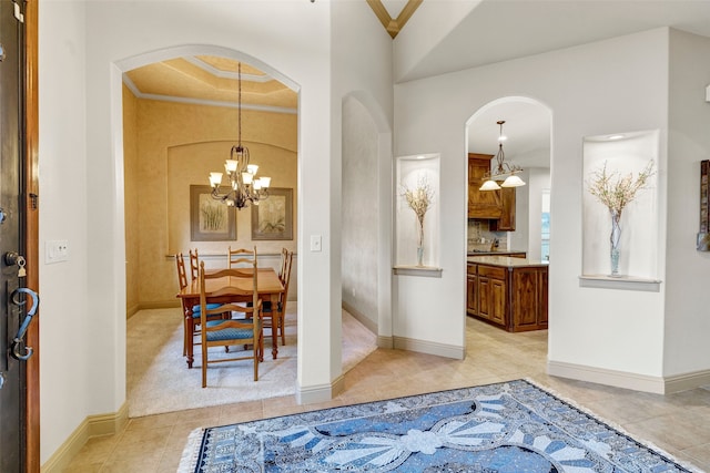 entrance foyer with baseboards, a chandelier, crown molding, and light tile patterned flooring