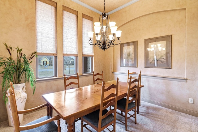 carpeted dining area featuring ornamental molding, an inviting chandelier, and baseboards