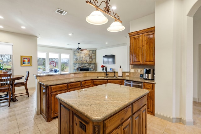 kitchen with visible vents, brown cabinetry, a kitchen island, a sink, and stainless steel dishwasher