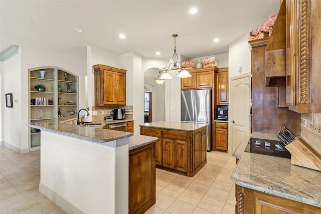 kitchen featuring stainless steel appliances, brown cabinetry, a sink, and light stone counters