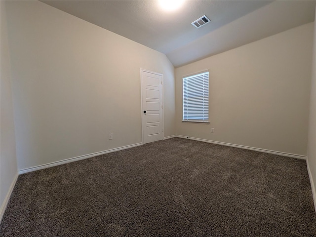 spare room featuring baseboards, vaulted ceiling, visible vents, and dark colored carpet