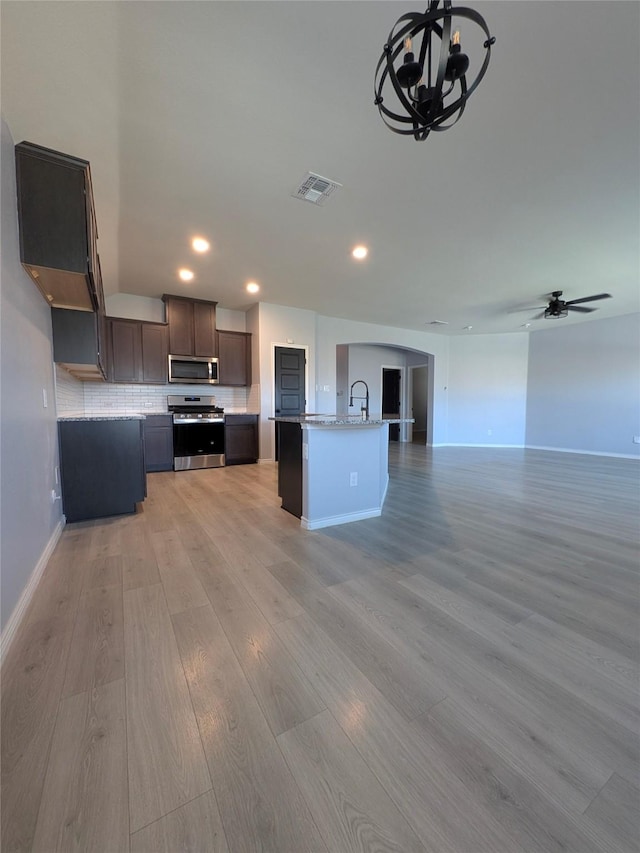 kitchen featuring light wood-style flooring, stainless steel appliances, a sink, visible vents, and open floor plan