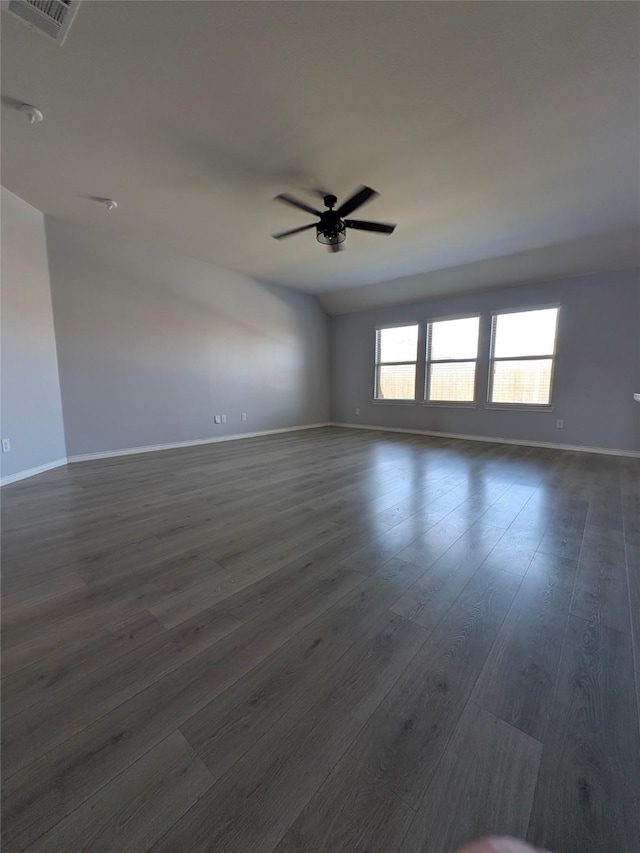 spare room featuring baseboards, dark wood-type flooring, visible vents, and a ceiling fan