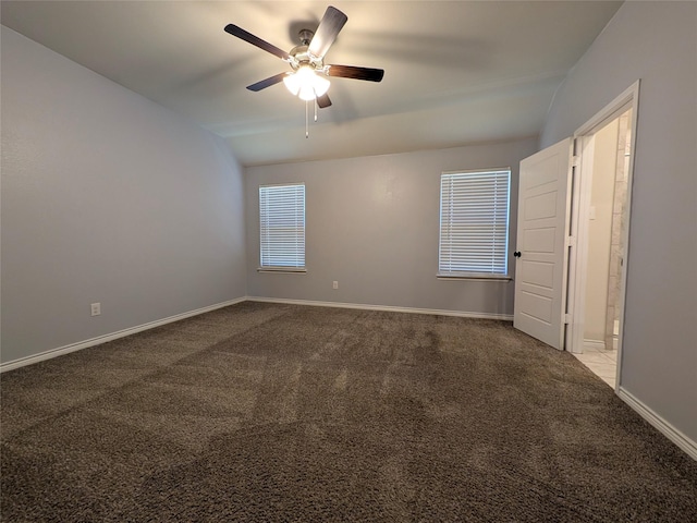 carpeted spare room with a ceiling fan, vaulted ceiling, and baseboards