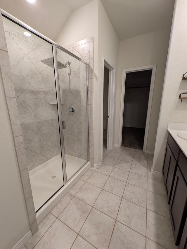 bathroom featuring a walk in closet, a shower stall, vanity, and tile patterned floors