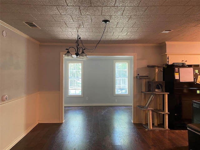 unfurnished dining area with visible vents, a wainscoted wall, dark wood-style floors, ornamental molding, and a chandelier