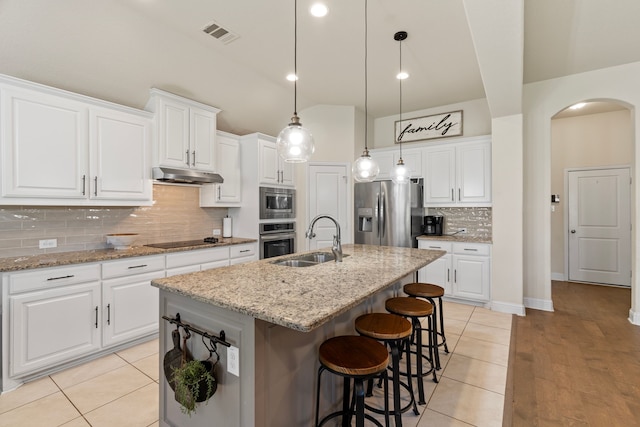 kitchen featuring visible vents, arched walkways, stainless steel appliances, under cabinet range hood, and a sink