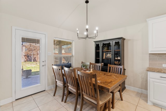 dining space featuring light tile patterned floors, baseboards, and an inviting chandelier