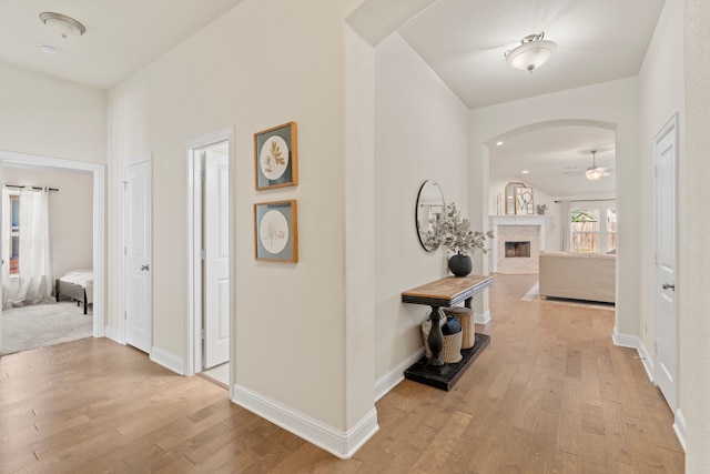 corridor featuring arched walkways, wood finished floors, and baseboards