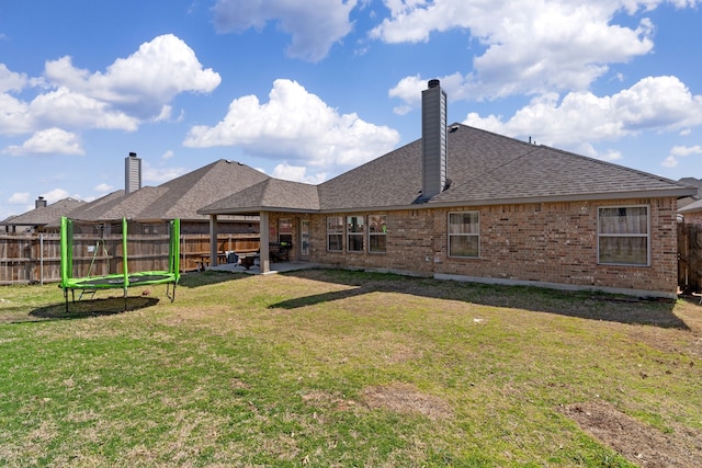 back of house with a lawn, a fenced backyard, a chimney, a patio area, and brick siding