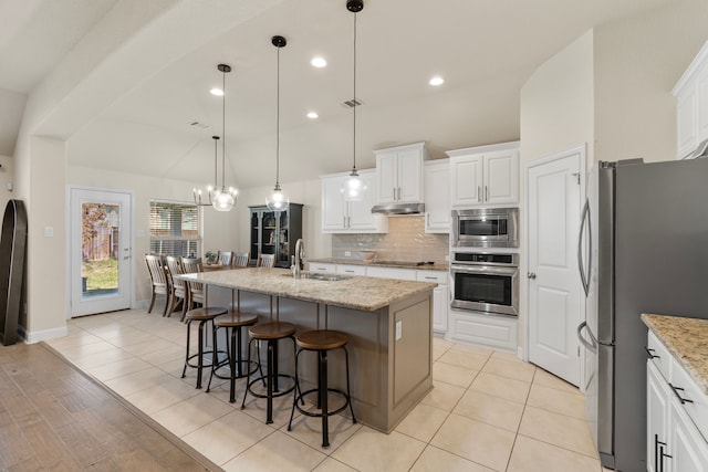 kitchen with tasteful backsplash, appliances with stainless steel finishes, a kitchen breakfast bar, under cabinet range hood, and a sink