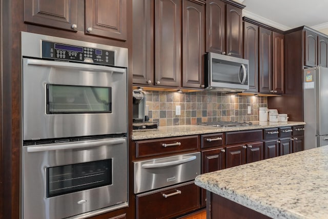 kitchen with dark brown cabinetry, decorative backsplash, light stone countertops, stainless steel appliances, and a warming drawer