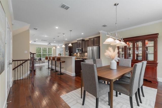 dining area with hardwood / wood-style flooring, visible vents, and crown molding