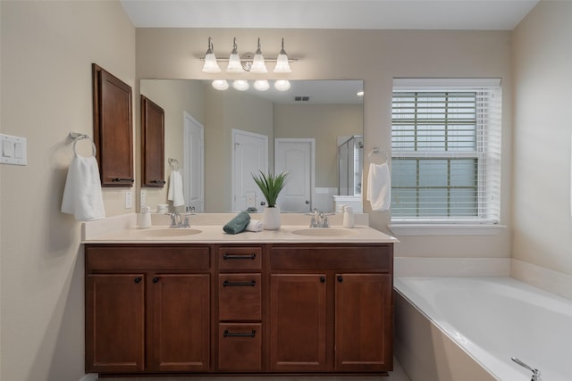 bathroom featuring visible vents, double vanity, a sink, and a bath