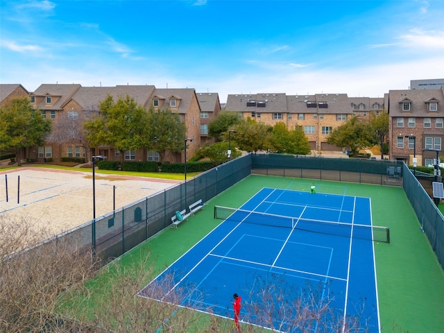 view of tennis court featuring fence and a residential view