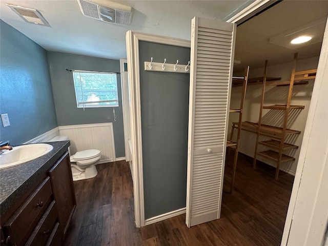 bathroom featuring toilet, visible vents, wood finished floors, and vanity