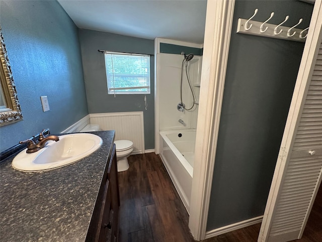 bathroom with toilet,  shower combination, wood finished floors, and vanity