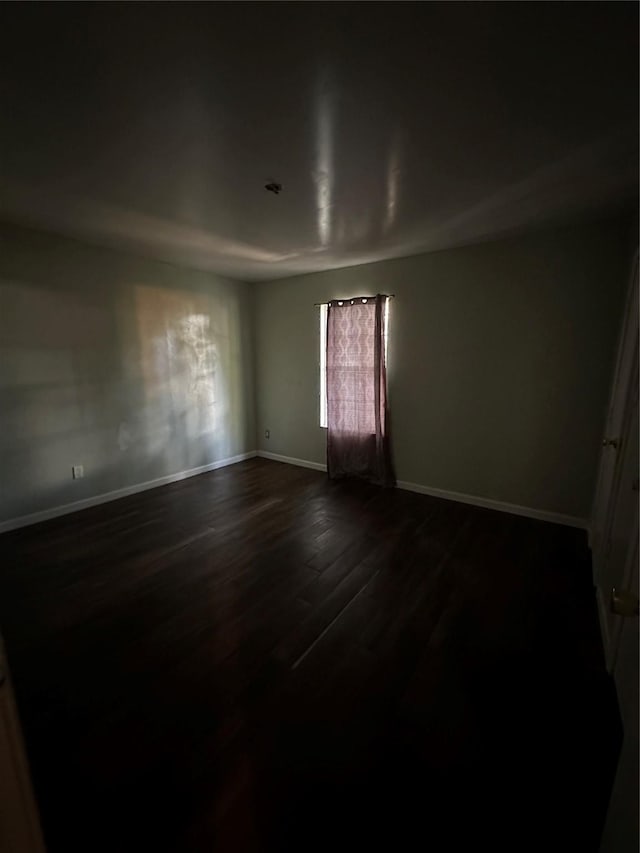 spare room featuring dark wood finished floors and baseboards