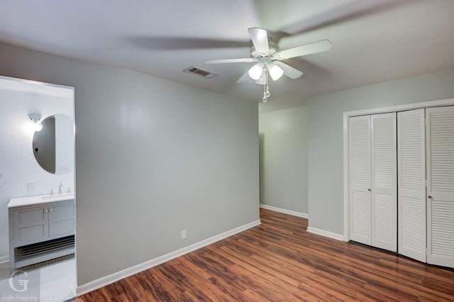 unfurnished bedroom with baseboards, visible vents, dark wood finished floors, ceiling fan, and a closet