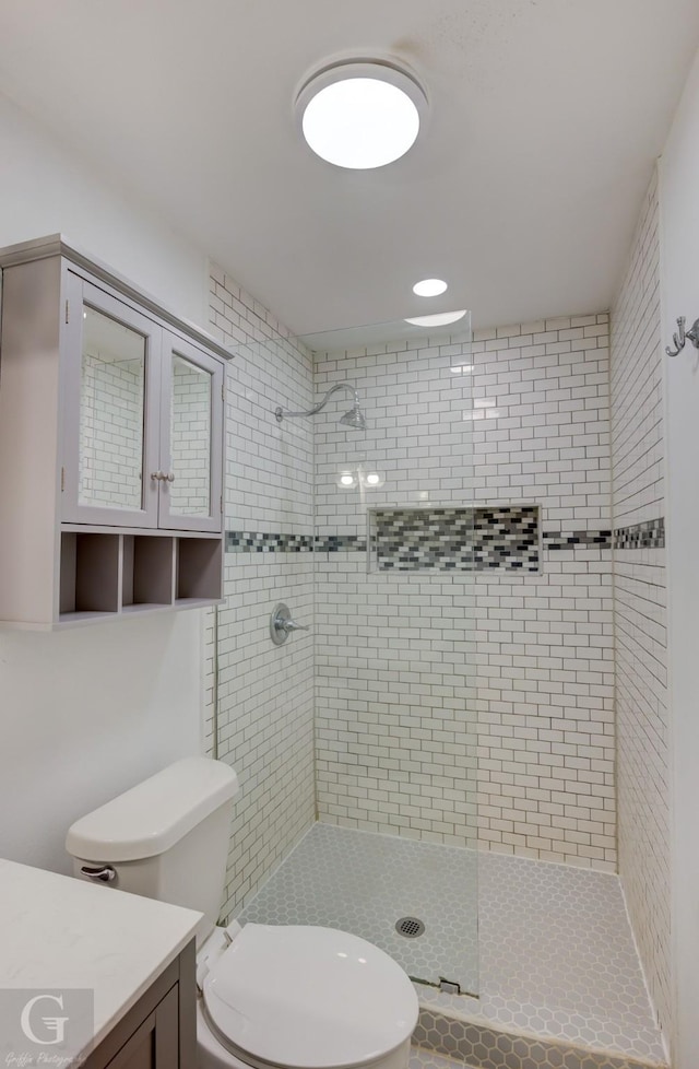 full bath featuring tiled shower, vanity, and toilet